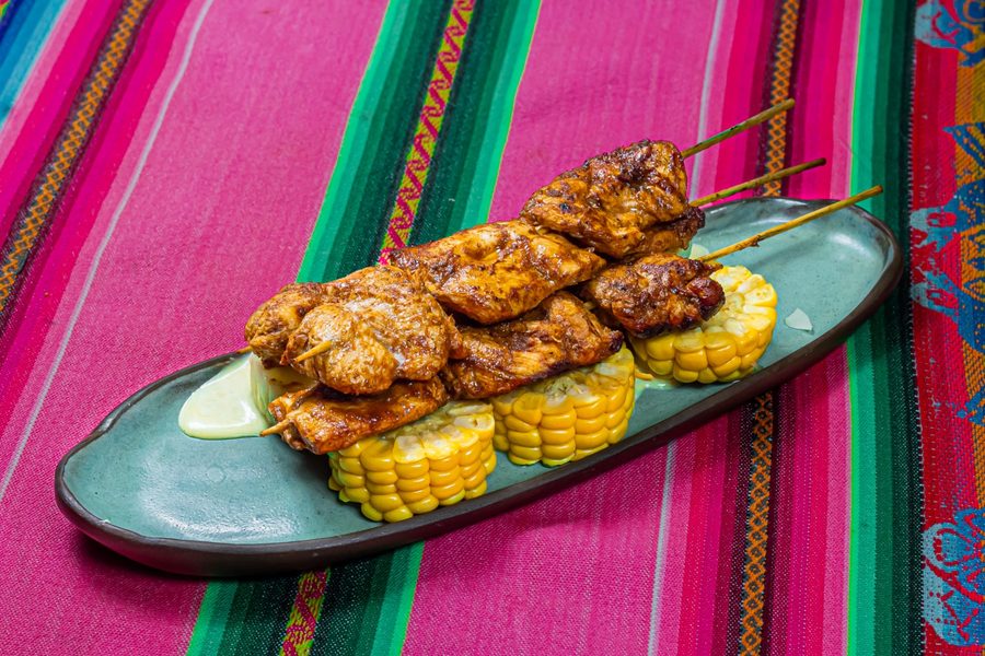 Anticuchos de pollo sobre choclo, con salsa huancaína