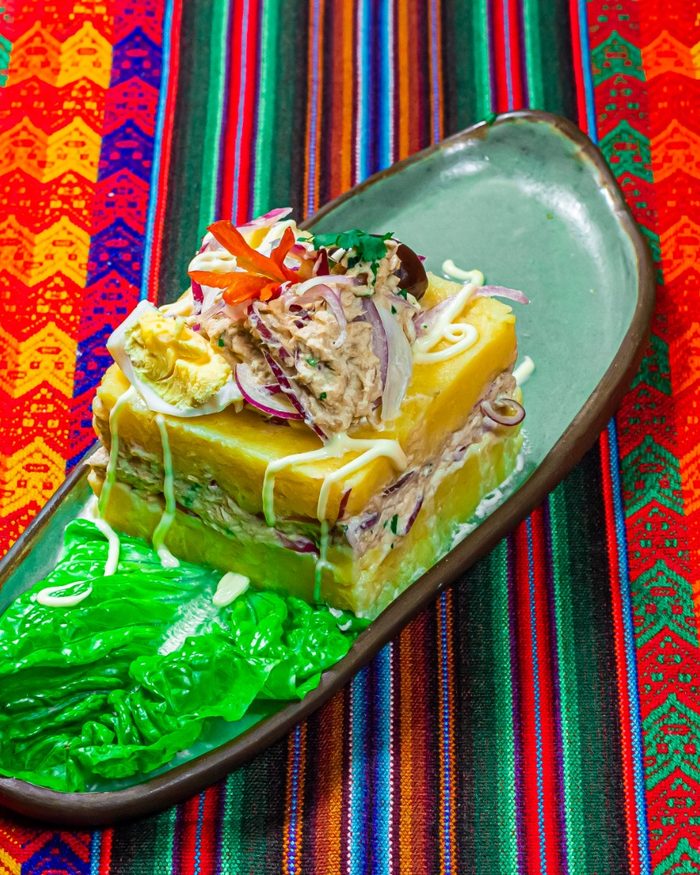 Causa de papa amarilla rellena, con salsa criolla y lechuga